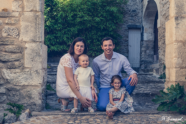 Photographie d'une famille sous une arche en pierre réalisée par Huitièm'art, photographe de baptême à Avignon (Vaucluse)