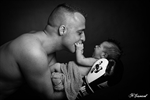 Photographie noir et blanc d'un papa avec des gants de boxe et de son bébé dans les gants de boxe réalisée par noelle gamand huitièm'art photographe nouveau né avignon vaucluse