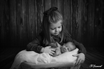 Photographie en noir et blanc  nouveau né  dans un panier avec sa grande soeur réalisée par noelle gamand  photographe avignon vaucluse