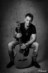 Photographie ne noir et blanc d'un musicien avec sa guitare assis par noelle gamand portraistide de france sur avignon vaucluse